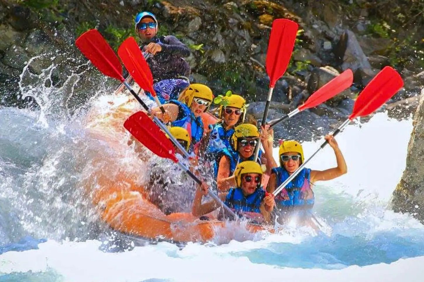 raft orange qui plonge dans une grosse vague? tout le monde a les pagaies en l'air