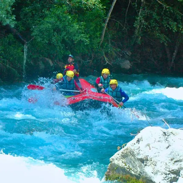 un raft en plein rapide, il y a beaucoup de vague et les pagayeurs sont éclaboussés